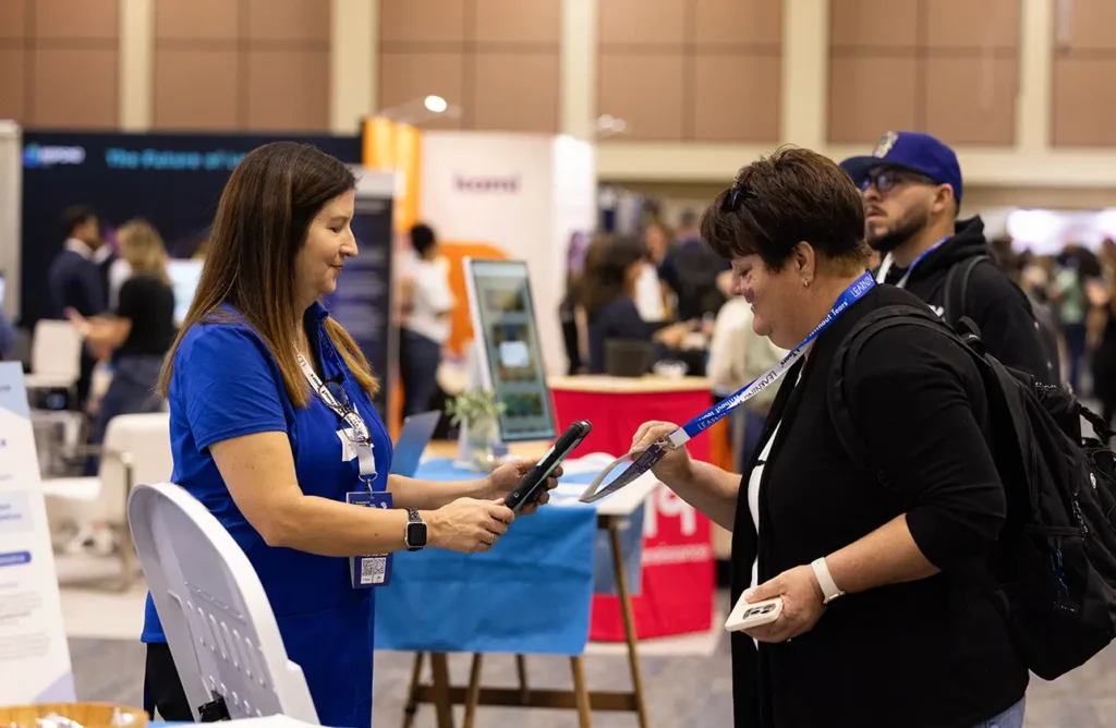 Exhibitor scanning an attendee badge inside the Spring CUE exhibit hall, showcasing active engagement and connection between educators and partners. 